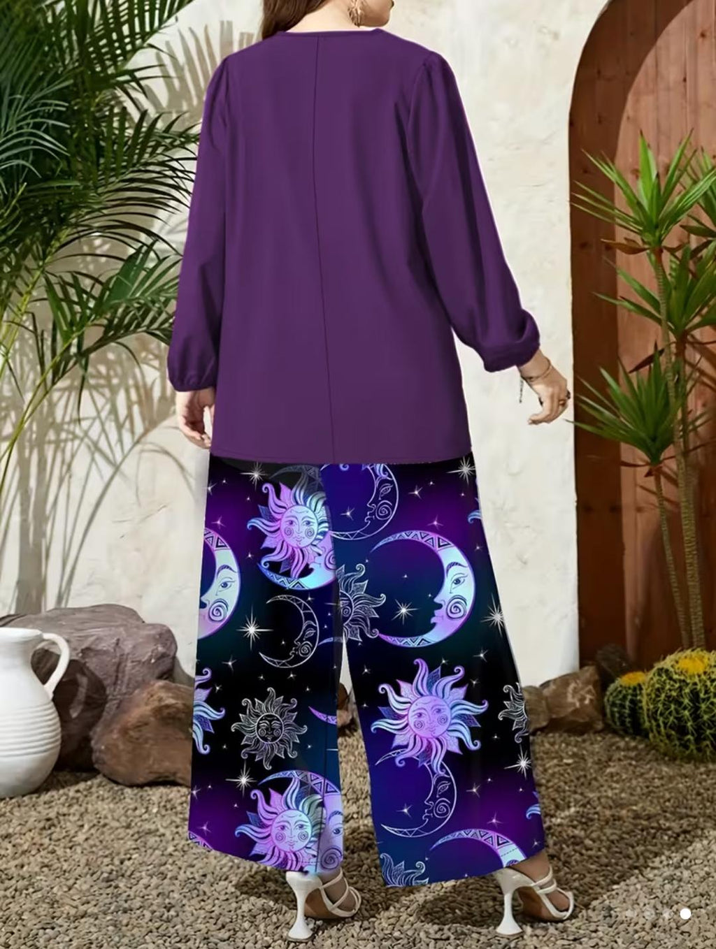 Blusa holgada en color violeta oscuro, diseñada con cuello en V y mangas largas con puños elásticos que aportan un toque elegante e informal, pantalon de pierna ancha con un llamativo estampado místico de sol, luna y estrellas.